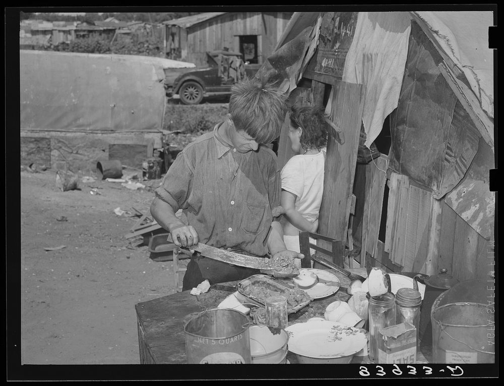 Boy living in camp near Mays Avenue making sandwich. This food is distributed by Saint Anthony's hospital after patients…