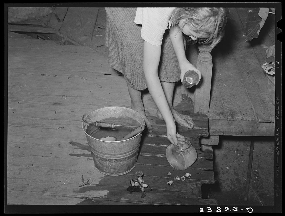 Daughter of tenant farmer living near Muskogee, Oklahoma, changing water in goldfish bowl. Refer to general caption number…