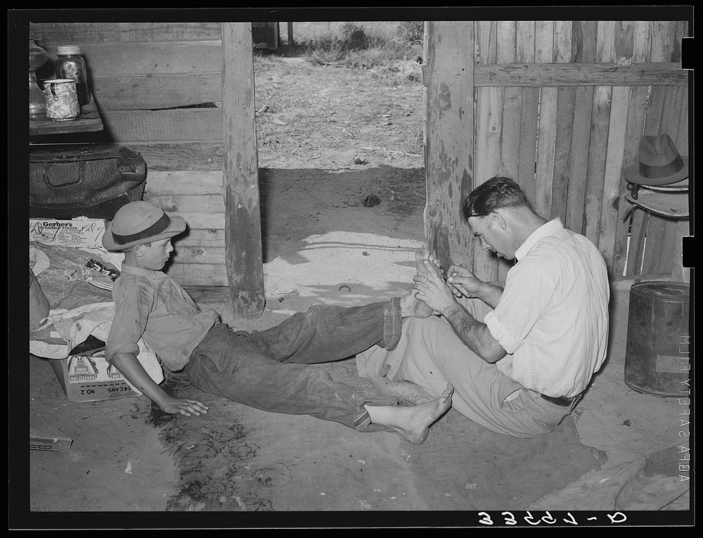 Resident of Mays Avenue camp, Oklahoma City, Oklahoma, taking piece of glass out of boy's foot. See general caption 21 by…