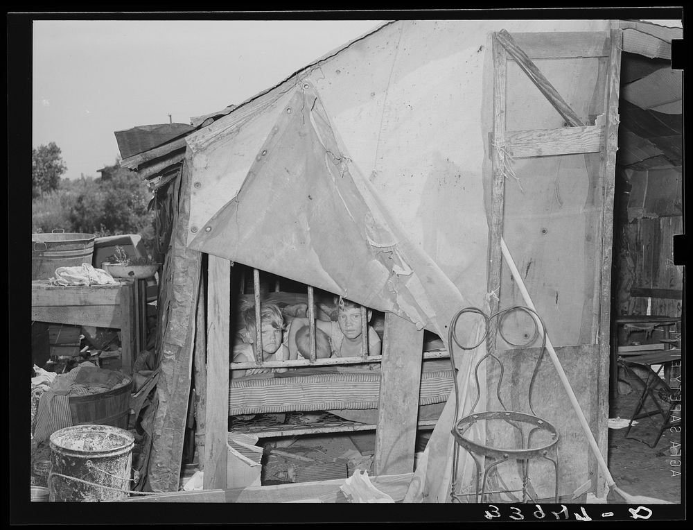 Children on bed inside of shack home in Mays Avenue camp. Oklahoma City, Oklahoma by Russell Lee