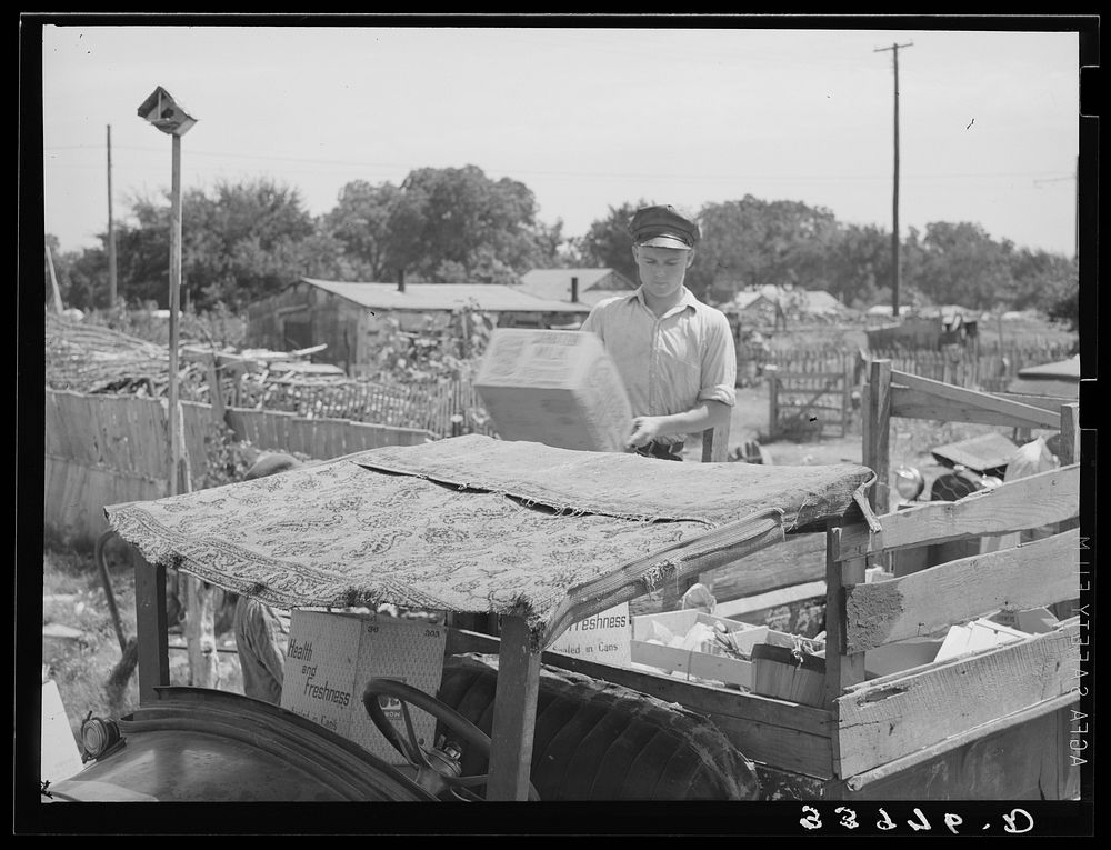 Top of oil truck made of old carpets. Boy is unloading discarded crates and overripe vegetables which he found in city…
