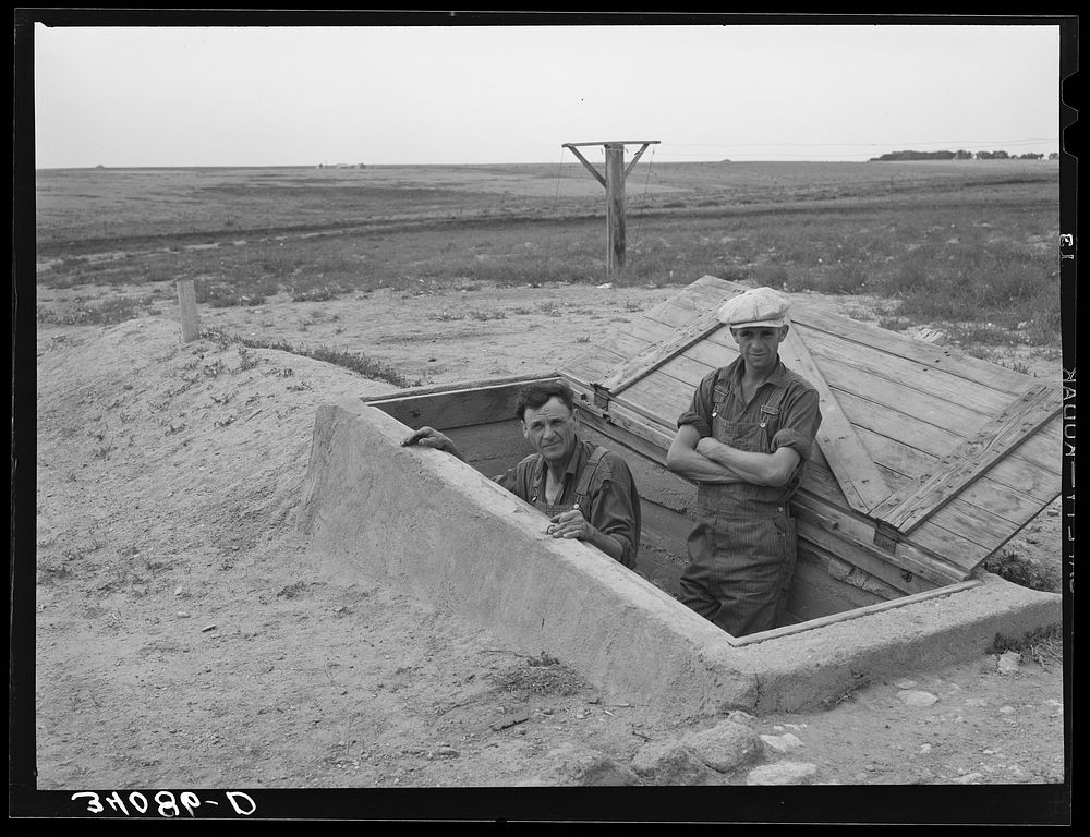 Mr. Shoenfeldt and son, FSA (Farm Security Administration) client in Sheridan County, Kansas, at entrance to fruit cellar…