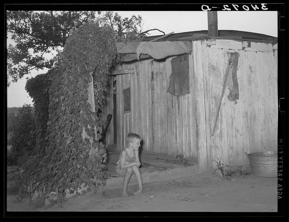 Young son of unemployed oil worker sitting on front porch of home. Seminole, Oklahoma by Russell Lee
