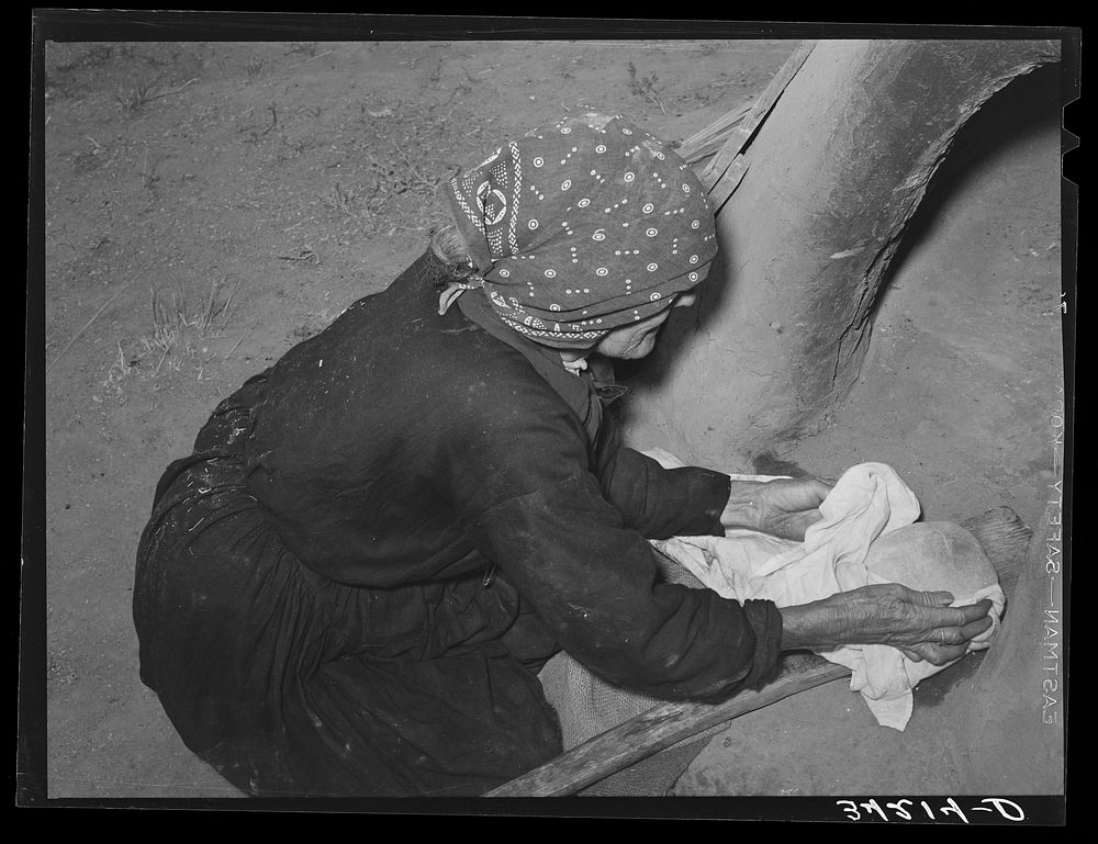 Spanish-American woman removing freshly baked bread from outdoor earthen oven near Taos, New Mexico by Russell Lee