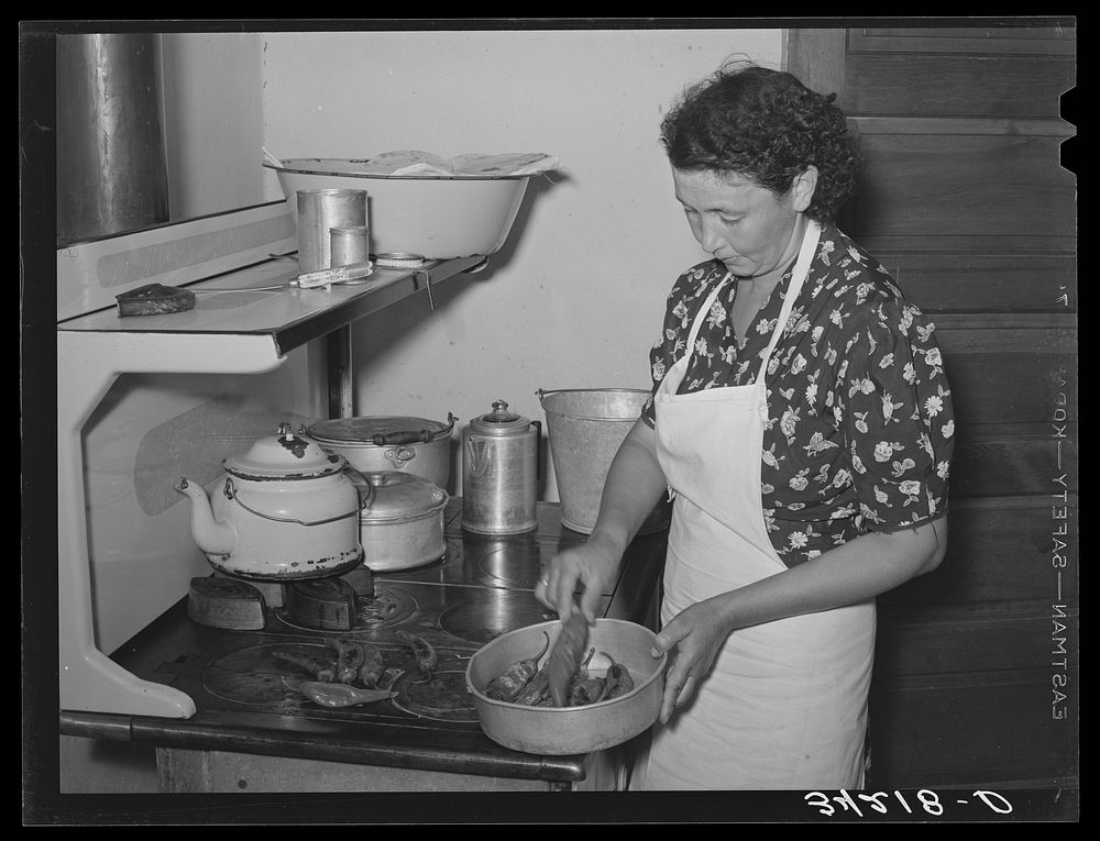 Spanish-American woman removing peppers from stove. Taos, New Mexico by Russell Lee