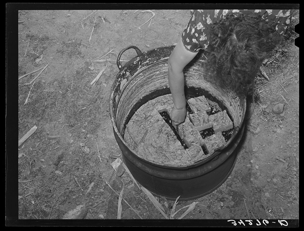 Spanish-American woman cutting soap which she made in this kettle. Near Taos, New Mexico by Russell Lee