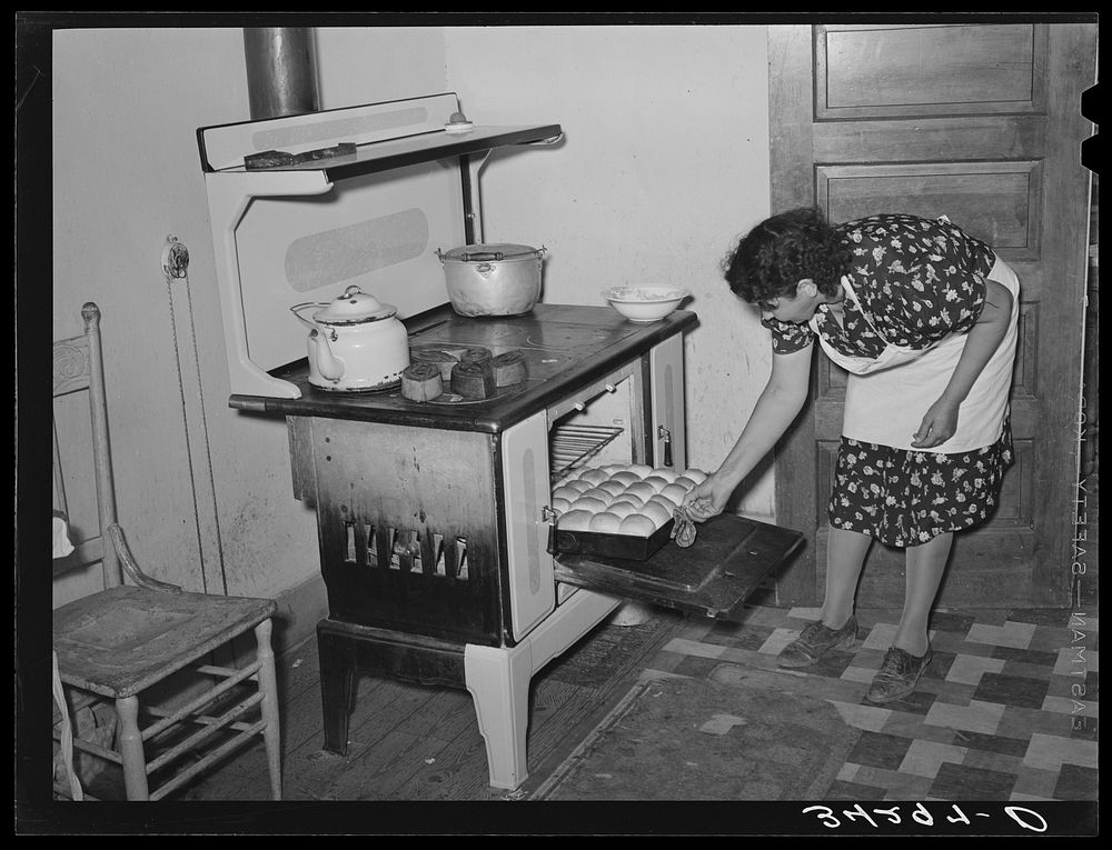 Spanish-American woman removing baked bread from oven farm near Taos, New Mexico by Russell Lee