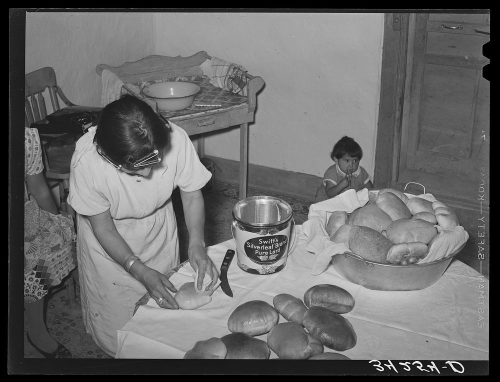 Brushing lard on freshly-baked bread in Spanish-American farm home near Taos, New Mexico by Russell Lee