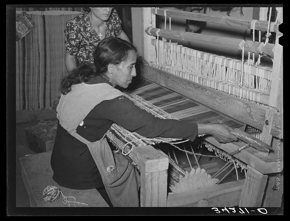 Spanish-American woman passing shuttle through warp in weaving rag rug. WPA (Works Progress Administration/Work Projects…