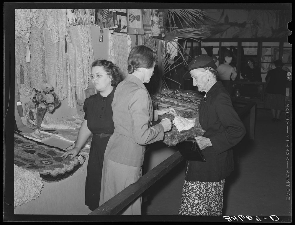 [Untitled photo, possibly related to: Women looking at quilting and crocheting exhibit at Gonzales County Fair. Gonzales…