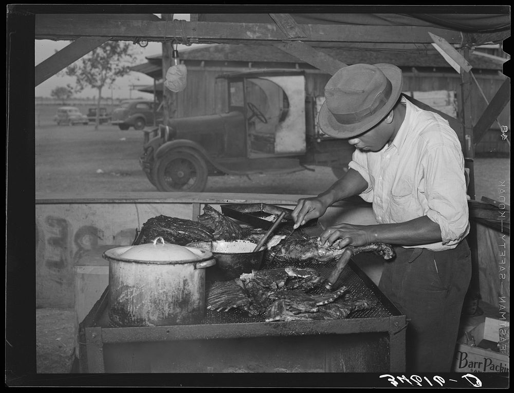 Man slicing barbecue at lunch stand at the Gonzales County Fair. Gonzales, Texas by Russell Lee