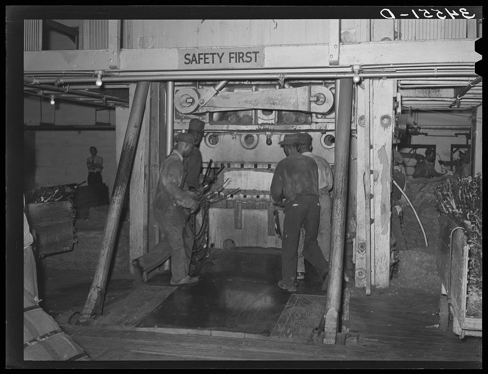  laborers placing bands around compressed bale of cotton. Compress, Houston, Texas by Russell Lee