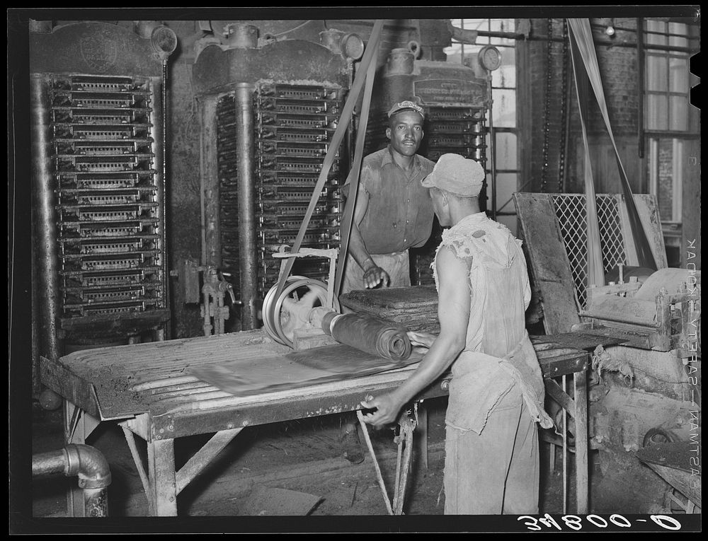 [Untitled photo, possibly related to: Workman removing cotton seed cake from mat after oil has been removed. The cake is…