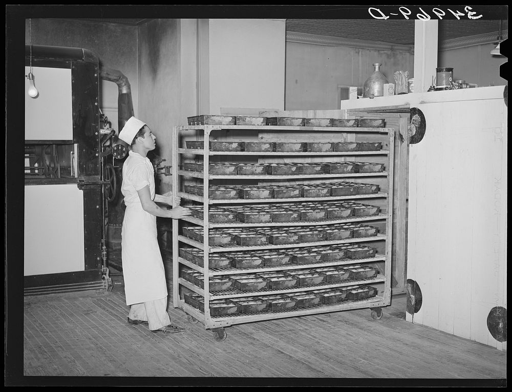 Moving trayload of bread and rolls into the rising compartment, which has regulated temperatures. Bakery, San Angelo, Texas…