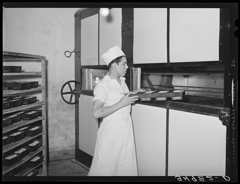 Putting loaves of bread into conveyor type oven for baking. Bakery, San Angelo, Texas by Russell Lee