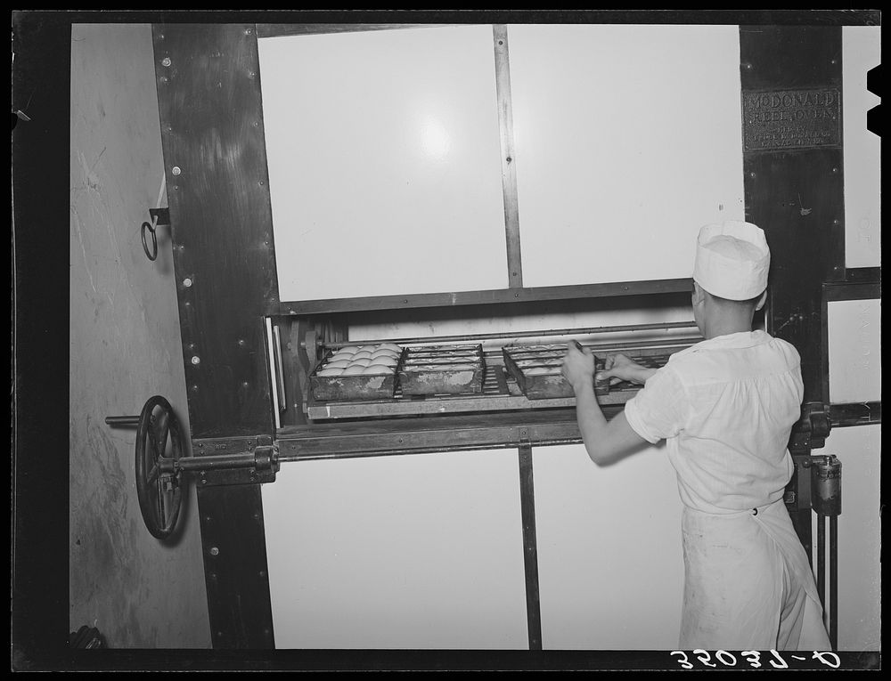 Placing rolls in reel oven to be baked. Bakery, San Angelo, Texas by Russell Lee