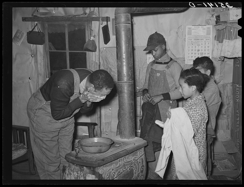 Pomp Hall,  tenant farmer, washing his face while his children stand by with towel and soap awaiting their turn at the…