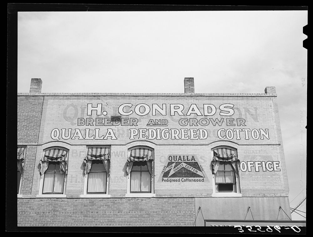 Sign on building in San Marcos, Texas. Cotton is the main crop in this section and farmers of German ancestry predominate by…