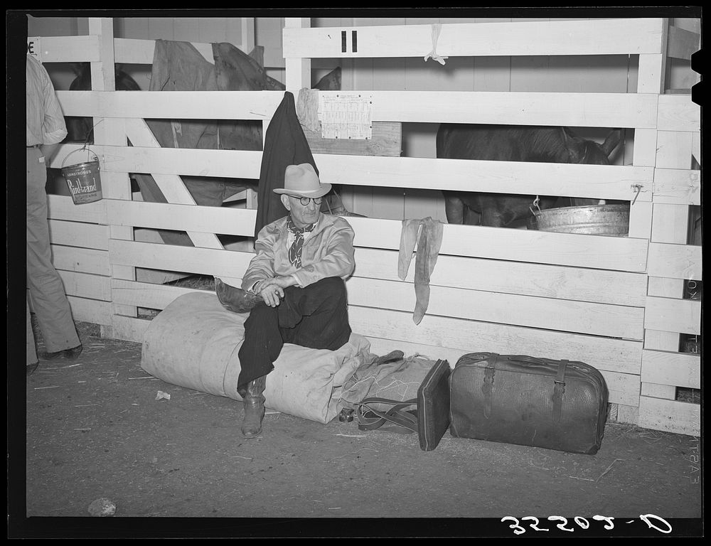Cattlemen sitting on rolled up camp bed in cattle barns at the San Angelo Fat Stock Show. San Angelo, Texas by Russell Lee