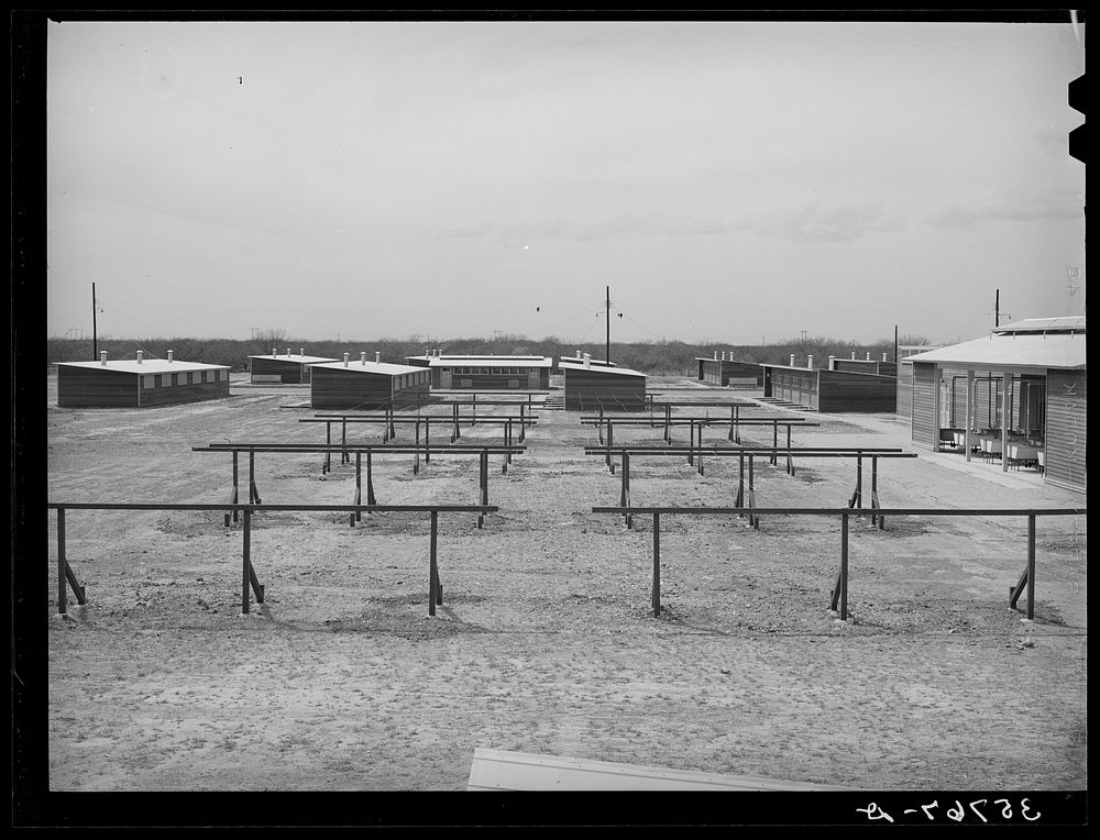 Clotheslines with laundry room at the right and row shelters in the background. Migratory labor camp, Sinton, Texas by…