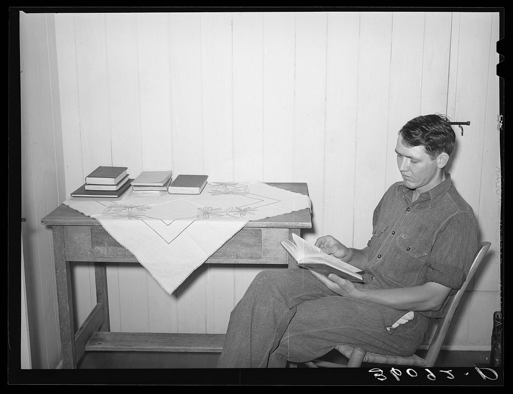 Member of the Arizona part-time farms, Chandler Unit, in bedroom of his apartment on the project studying for civil service…