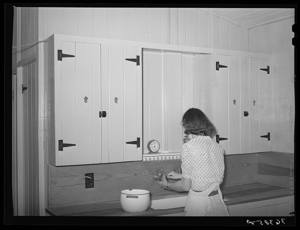 Wife of member of the Casa Grande Farms working at her kitchen sink. Pinal County, Arizona by Russell Lee