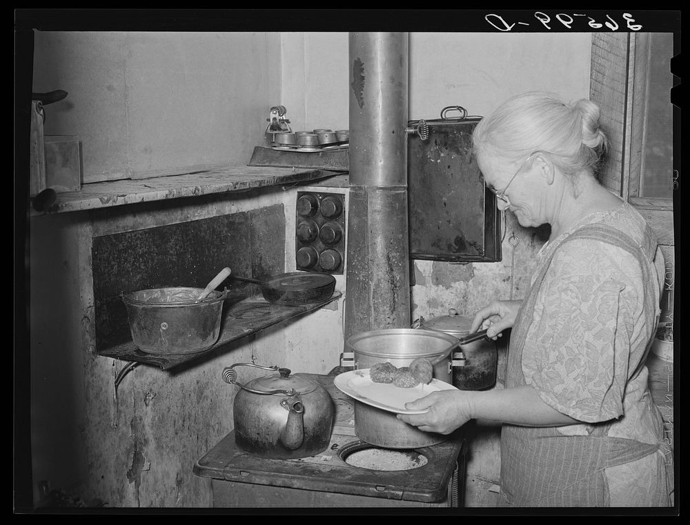 Mrs. George Hutton dishes up sausage made from her own hogs and canned last winter. Pie Town, New Mexico by Russell Lee