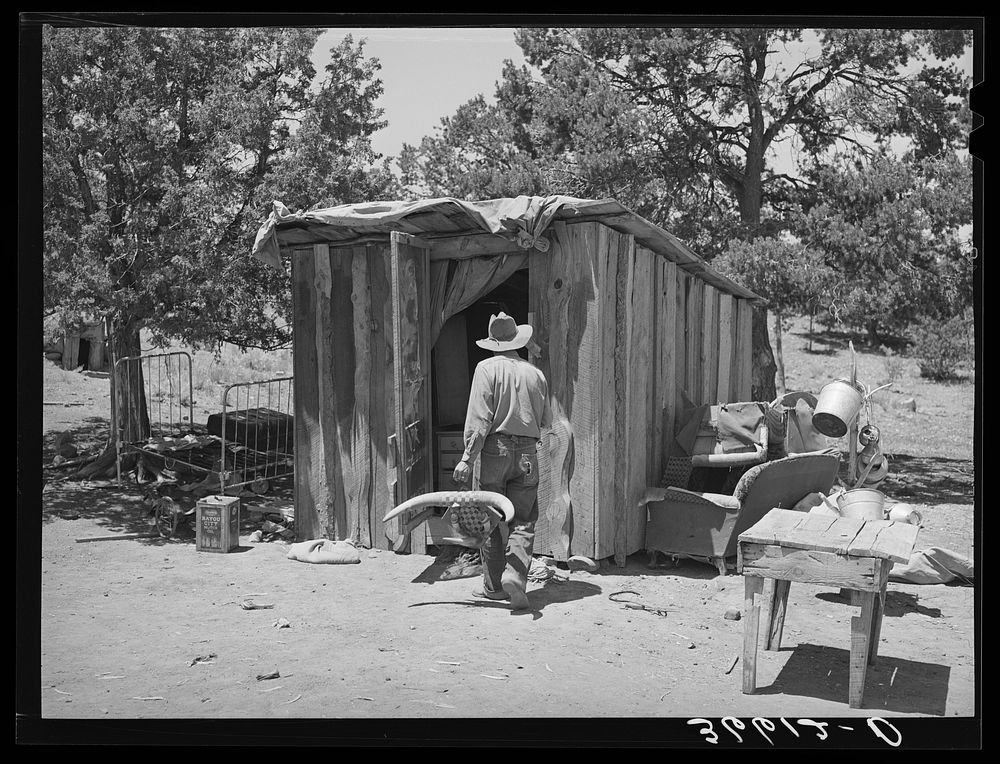 Faro Caudill taking household articles into shed for storage while he moves his dugout. Pie Town, New Mexico by Russell Lee