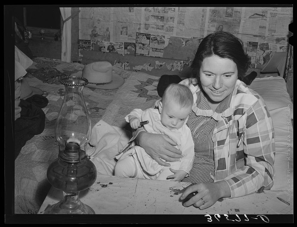 Mrs. Holley holding her baby while playing Fforty-two at party after literary society meeting. Pie Town, New Mexico. Mrs.…
