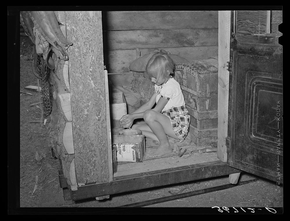 Daughter of homesteader getting chicken feed in slab shed. Trunk seen through the doorway was used to bring personal affects…