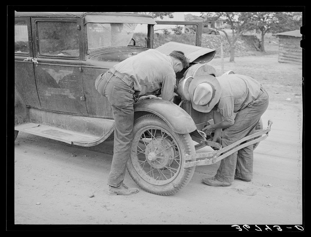 [Untitled photo, possibly related to: Garage owner and farmer working on a car. Pie Town, New Mexico. The young man who owns…