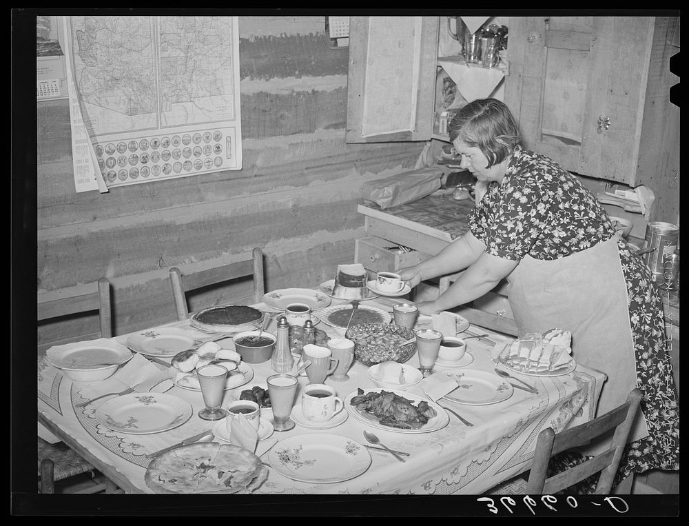 Mrs. Bill Stagg, homesteader's wife, putting the coffee on the table for dinner. For dinner there was home-cured ham and…
