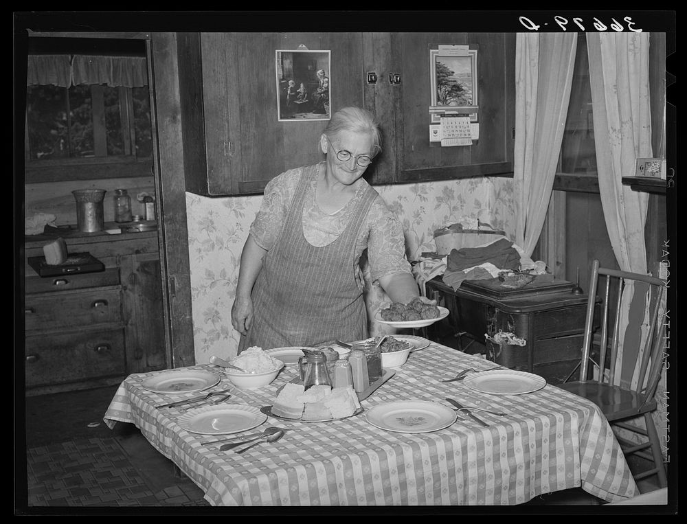 Mrs. George Hutton putting the food on the table for dinner. Pie Town, New Mexico by Russell Lee