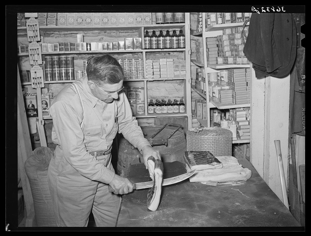 Mr. Keele slicing bacon in the general store at Pie Town, New Mexico by Russell Lee