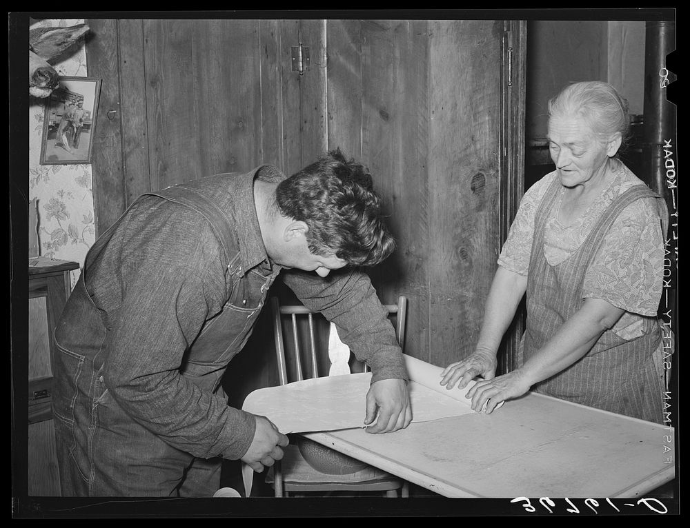 Mrs. George Hutton and her son measure off paper for the kitchen. Pie Town, New Mexico by Russell Lee