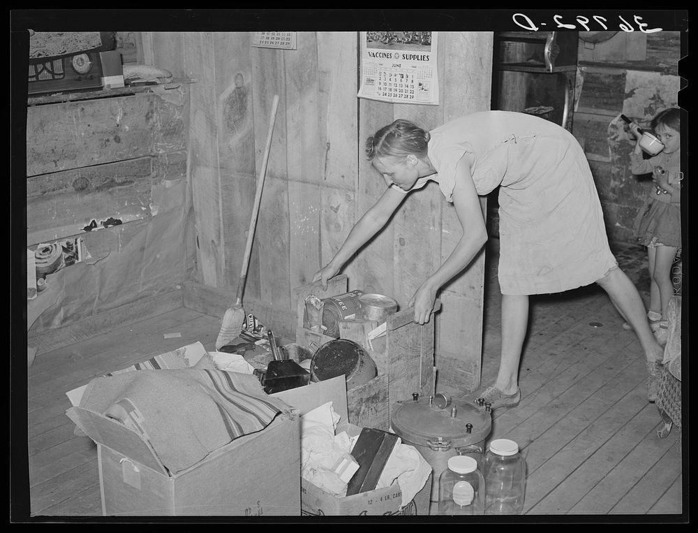 Mrs. Faro Caudill packing up kitchen equipment for moving to new dugout nearer the well. Notice the pressure cooker. These…