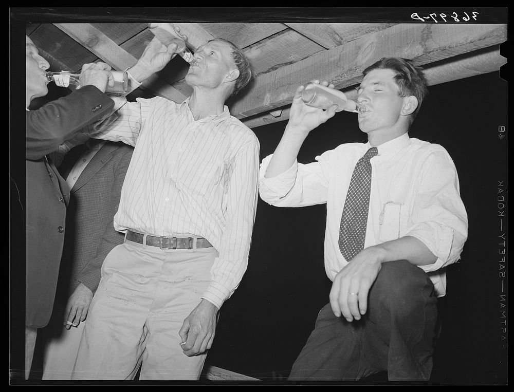 The men have a bottle of beer at the square dance. Pie Town, New Mexico by Russell Lee