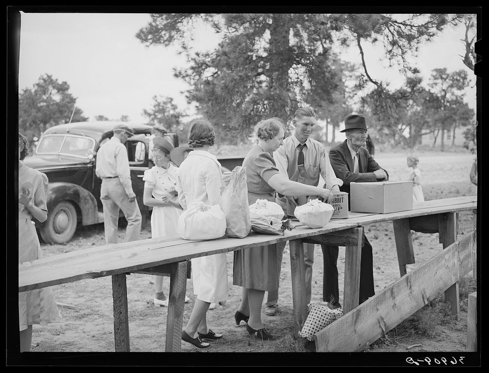 Putting out the food for "Dinner on the Grounds" at all-day community sing. Pie Town, New Mexico by Russell Lee