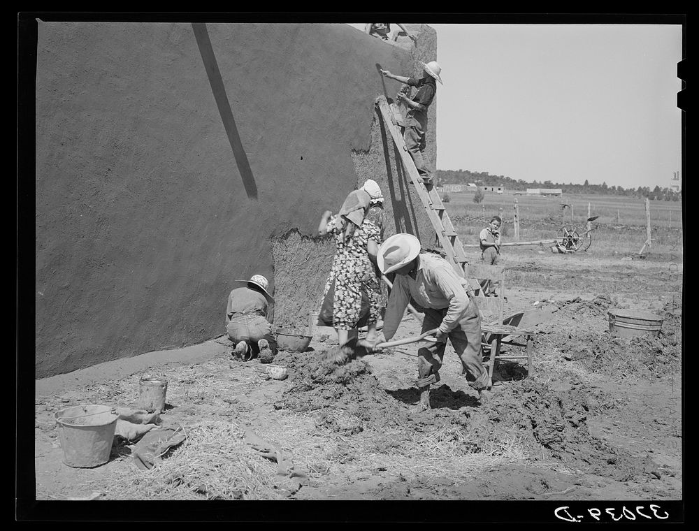 [Untitled photo, possibly related to: Mixing plaster for house, Chamisal, New Mexico. Occasionally a man helps with the hard…