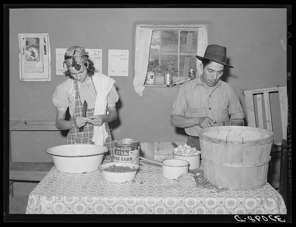 Spanish-American couple preparing fruit for canning. Chamisal, New Mexico by Russell Lee