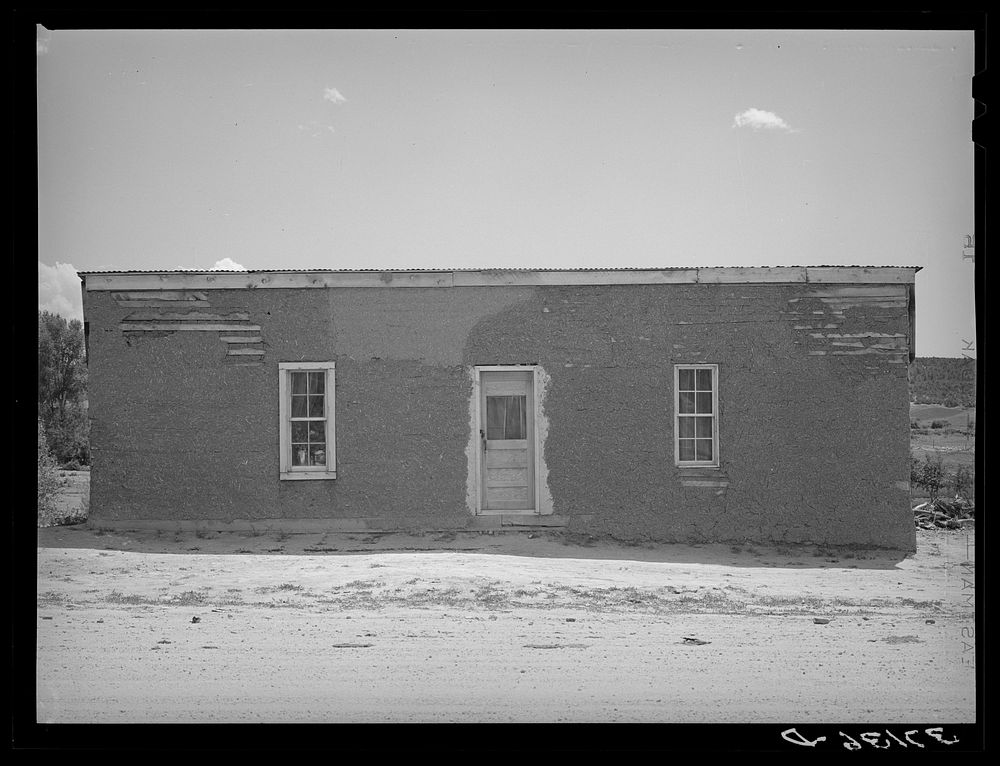 Front of Spanish-American house, Penasco, New Mexico. Notice the small windows, however; because of the brilliant suns in…