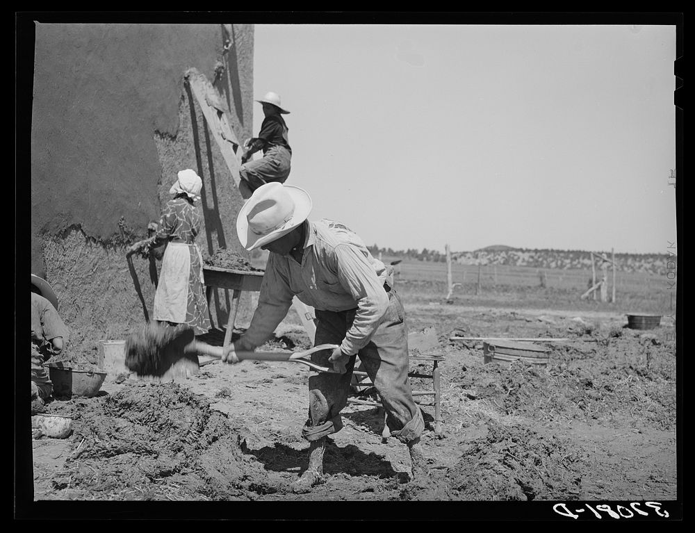 Mixing plaster for house, Chamisal, New Mexico. Occasionally a man helps with the hard work of mixing plaster but the women…
