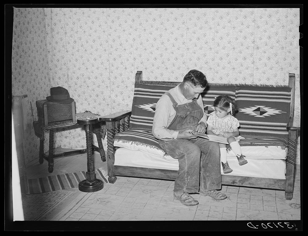 Spanish-American farmer and his daughter seated on couch which his son made at school workshop in Albuquerque. Chamisal, New…