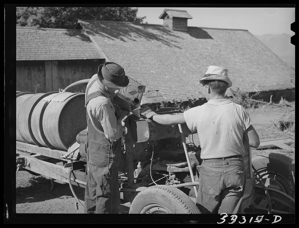 Pouring gasoline into tank of converted automobile which supplies power for FSA (Farm Security Administration) cooperative…