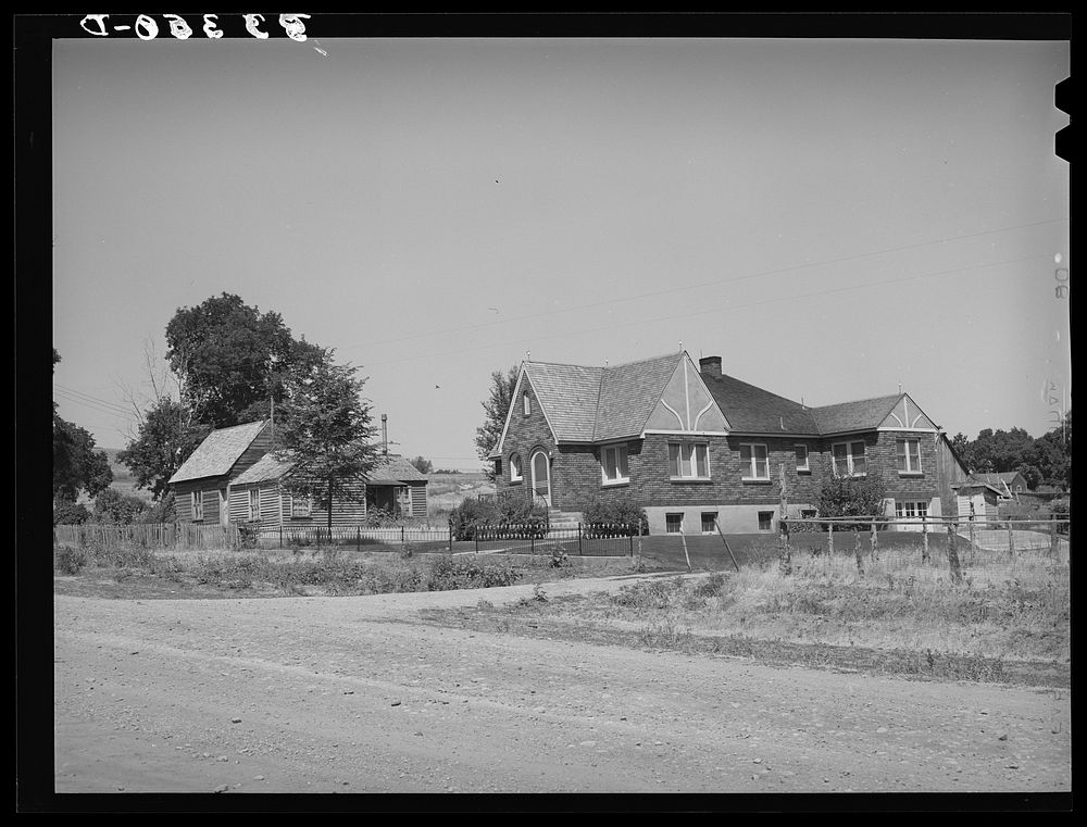 Houses belonging to a Mormon farmer in Mendon, Utah. The new house was built with profits from his farm by Russell Lee