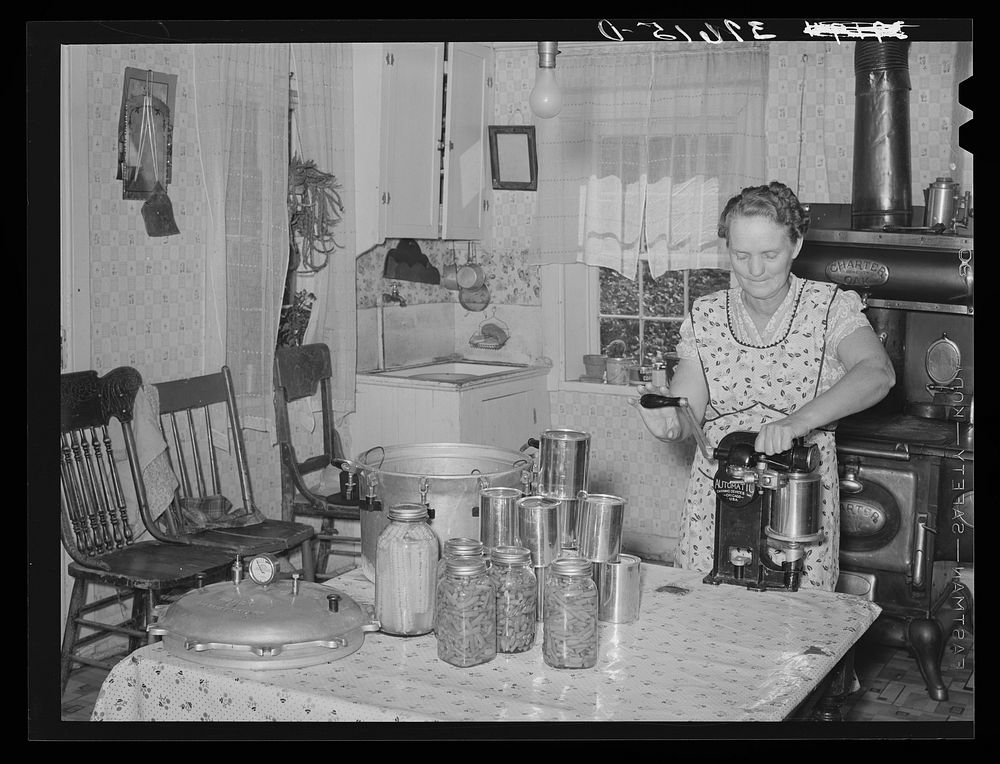 Mrs. Christiansen of the Christiansen canning unit sealing cans. During 1939 she canned 2300 quarts which included 20…
