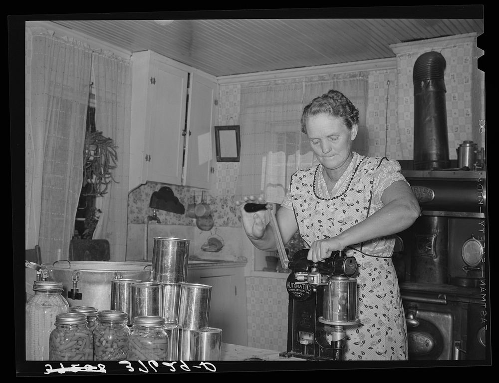 Mrs. Christiansen of the Christiansen canning unit sealing cans. During 1939 she canned 2300 quarts which included 20…