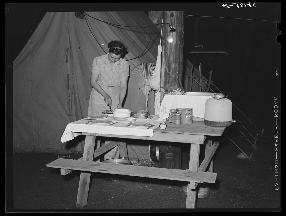 Carpenter's wife setting the table in front of their tent home. Mission Valley, California, which is about three miles from…