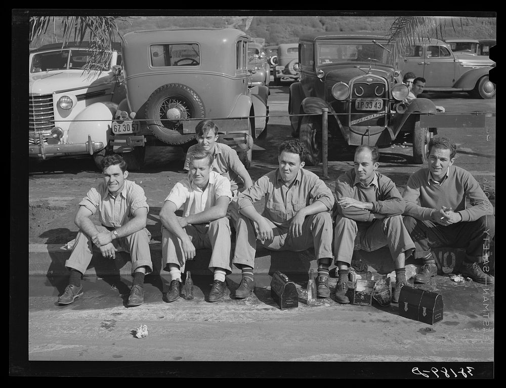Workers eating lunch on curb across the street from the Consolidated Airplane Factory. San Diego, California by Russell Lee