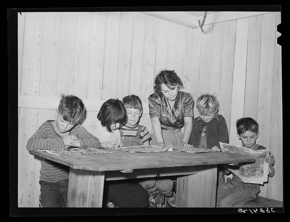 Six children of carpenter from Hobbs, New Mexico, reading the funny papers. This family of eight are living in two small…